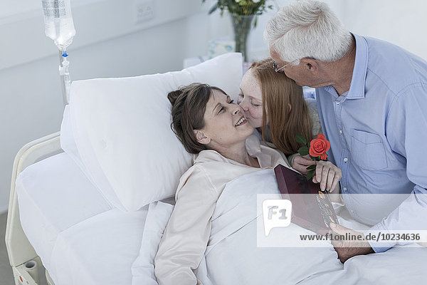 Husband and granddaughter visiting mature patient in hospital