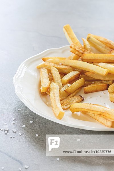 Pommes frites auf weissem Teller mit Meersalz