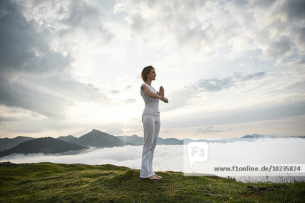 Österreich  Kranzhorn  Mittlere erwachsene Frau beim Yoga auf dem Berggipfel