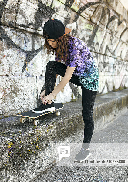 Weibliche Skateboarderin  die ihren Schuh bindet.