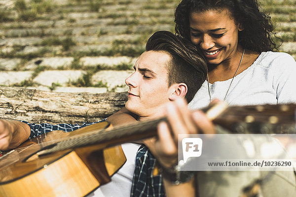 Entspanntes junges Paar mit Gitarre im Freien
