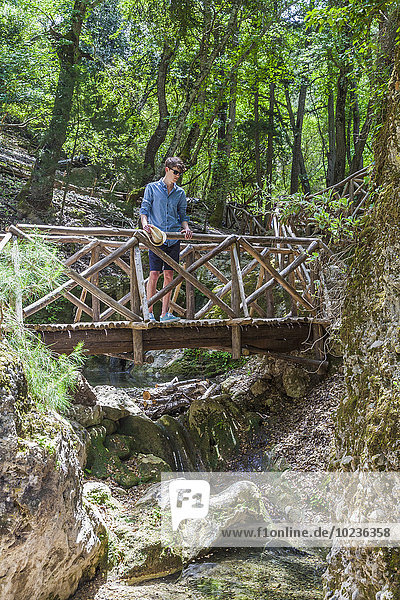 Greece  Rhodes  young man standing on wooden bridge in the wood