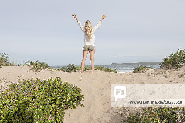 Südafrika  Kapstadt  Rückansicht einer Frau  die auf einer Stranddüne steht.