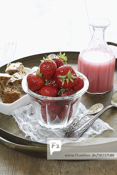 Frische Erdbeeren im Glas und selbstgemachte Erdbeermilch  dahinter Schälchen mit Topfkuchenstücken