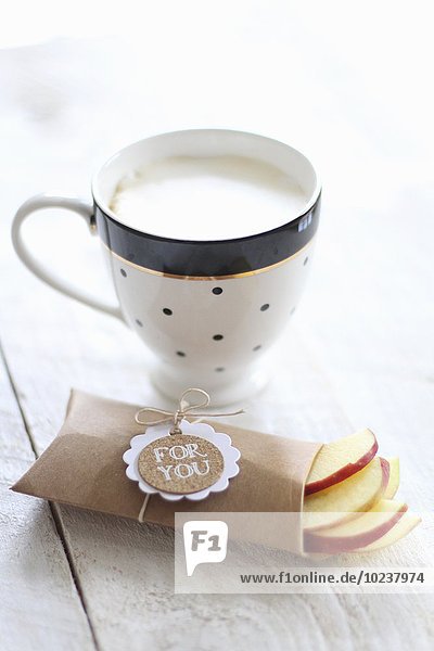 Eine Tasse Milchkaffee und frische Apfelscheiben