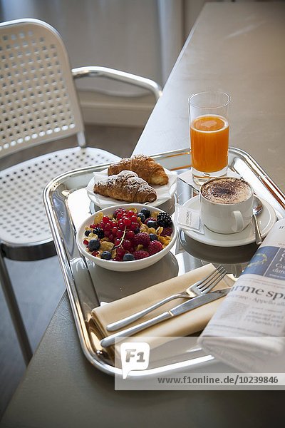 Frühstück mit Croissants  Cappuccino  Orangensaft und Cerealien mit frischen Beeren
