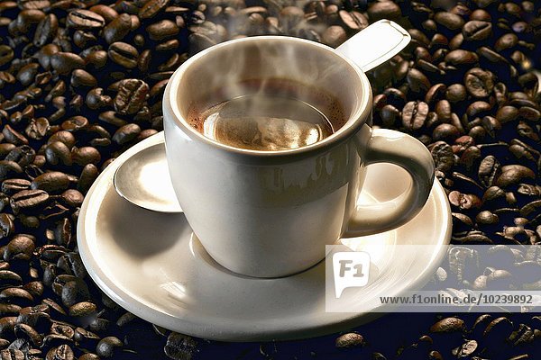 Dampfende Espressotasse auf gerösteten Kaffeebohnen