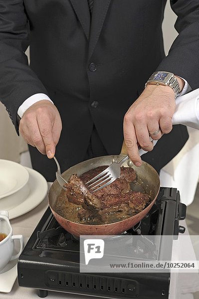 Preparing steak with black pepper sauce on a carving table