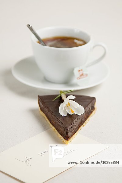 Slice of chocolate tart cup of coffee and a note
