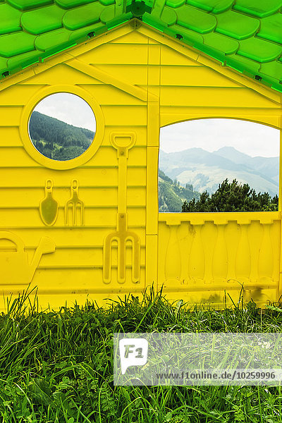 Außenansicht des gelben Hauses mit Spiegelungen von Bergen an den Fenstern