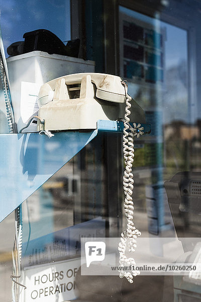 Old-fashioned telephone by glass wall