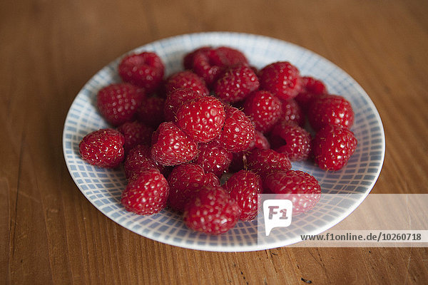 Raspberries in plate on wooden table