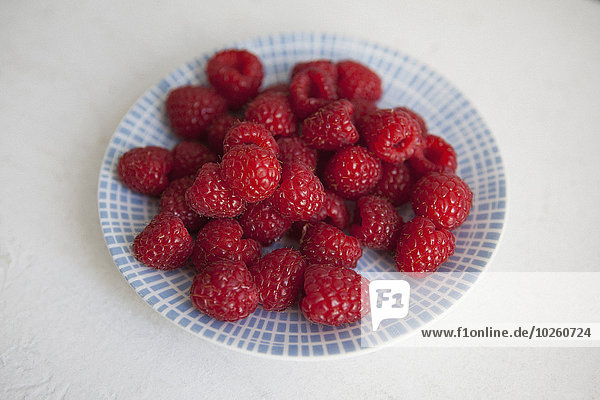 Raspberries in plate on white background