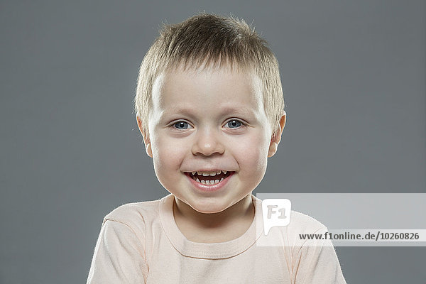 Porträt des glücklichen Jungen vor grauem Hintergrund