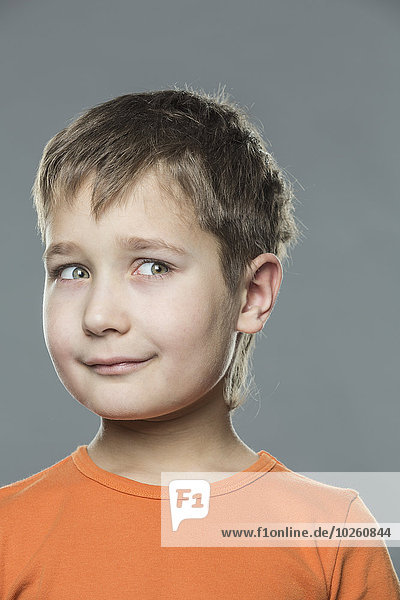 Thoughtful boy looking away against gray background