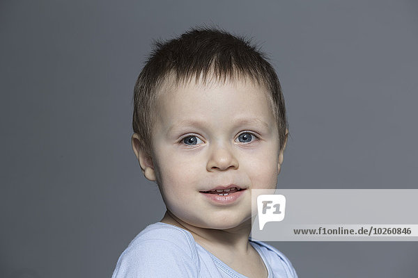 Portrait of cute boy against gray background