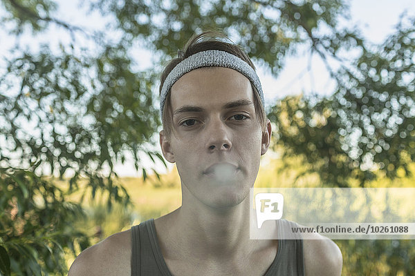Porträt eines jungen Mannes  der im Freien raucht