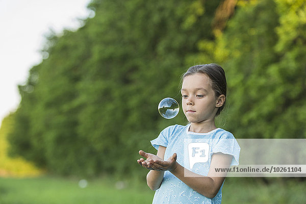Mädchen spielt mit Seifenblase im Freien