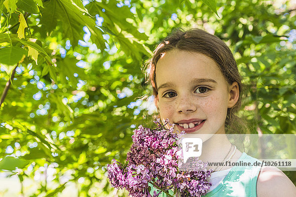Porträt eines glücklichen Mädchens mit lila Blumen im Freien
