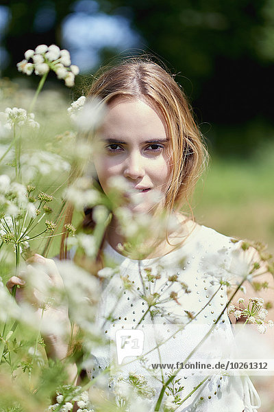 Porträt einer jungen Frau  die an Blumenpflanzen im Park steht.