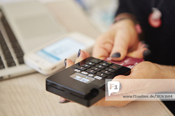 A woman's hands holding a credit card reader  processing payment or paying for goods.