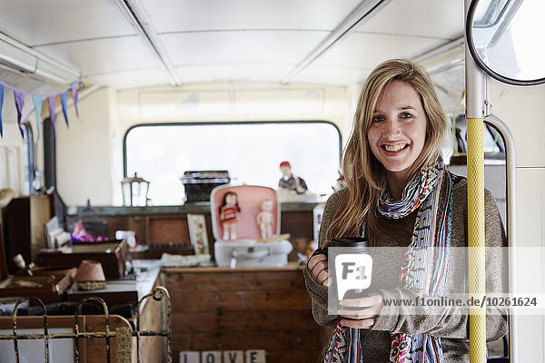A woman standing in a bus converted into a vintage shop at a flea market surrounded by vintage objects.