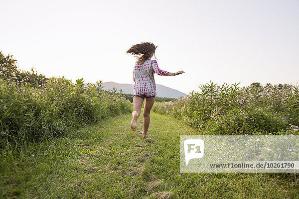 A woman running along a path in a meadow.