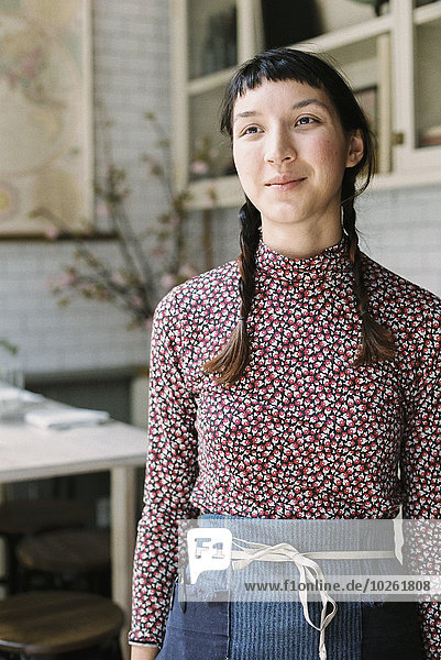 A woman with braids wearing an apron  a waitress in a restaurant.