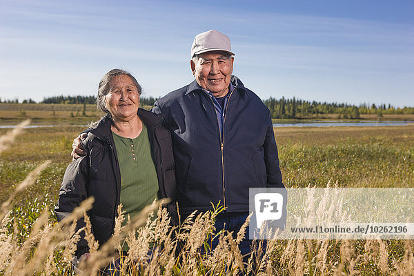 Elderly Alaska native couple pose while standing amongst grasses  Shungnak  Arctic Alaska  summer