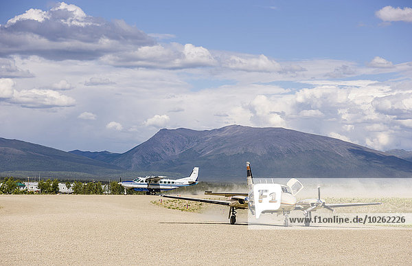 Airplanes on a dirt landing strip at the Shungnak Airport with Cosmos Mountain in the background  Arctic Alaska  summer