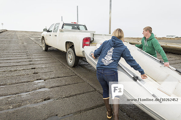 Young adults loading a rubber skiff onto a boat trailer on a boat ramp  Homer Spit  Kenai Peninsula  Southcentral Alaska