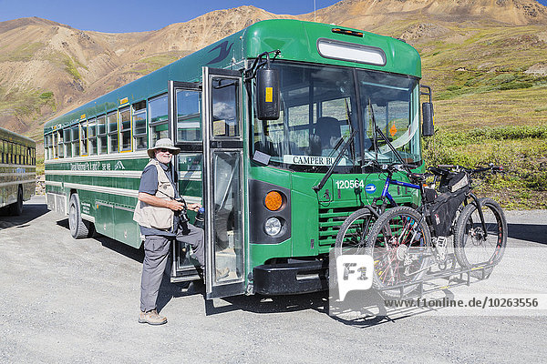 A male tourist with a camera enters a park camper bus at Eielson Visitor Center in Denali National Park  Interior Alaska  Summer  USA.