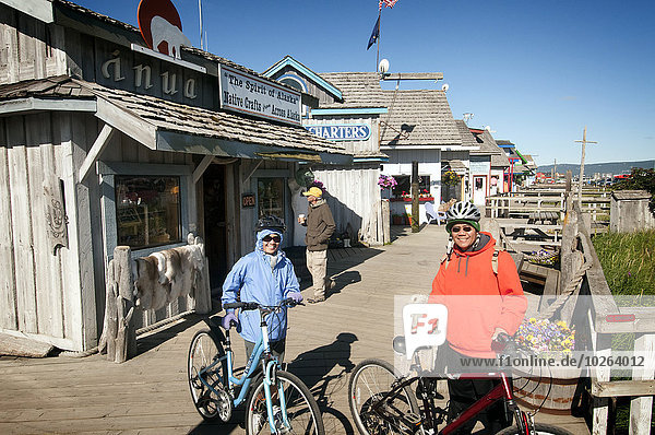 Bicyclists enjoy shopping along the boardwalk businesses on the Homer Spit  Southcentral Alaska  Summer