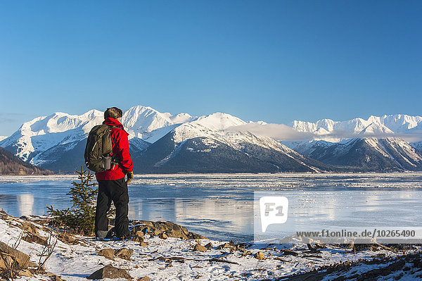 A man snowshoeing along the Cook Inlet with Kenai Mountains in the background  Southcentral Alaska  Winter