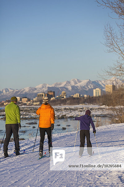 People cross country skiing on the Tony Knowles Coastal Trail near Earthquake Park with Anchorage skyline in the background  Cook Inlet  Southcentral Alaska