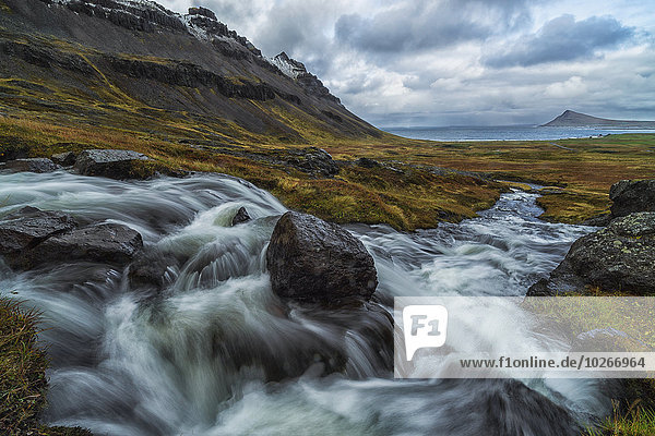 A large stream runs down a hillside creating a waterfall along the Strandir Coast in the West Fjords of Iceland; Iceland