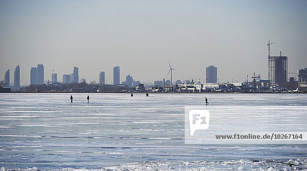 People in the distance on the ice against city skyline from Ward's Island; Toronto  Ontario  Canada