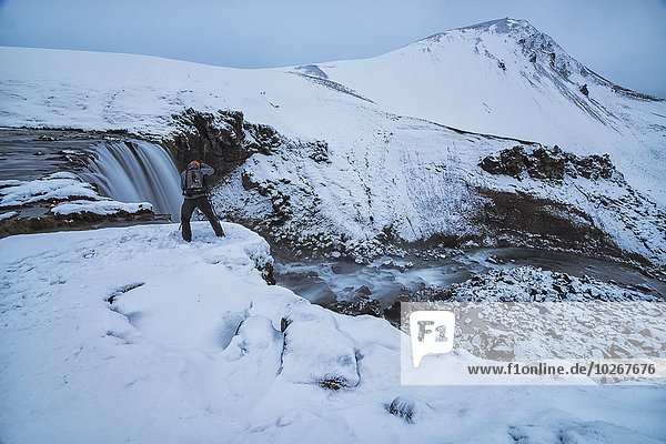 Photographer taking photographs at the top of an unnamed waterfall in the highlands of Iceland; Iceland