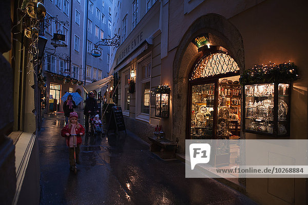 A family strolls past an antique shop in the pedestrianised streets of the old city on a rainy day; Salzburg  Austria