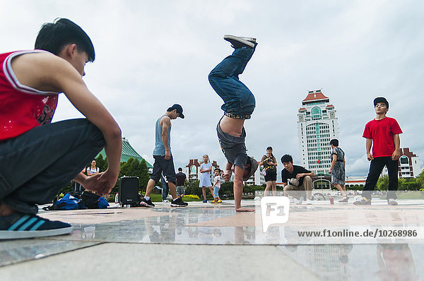 A street dancer doing acrobatics next to Xiamen University's lake; Xiamen  Fujian Province  China