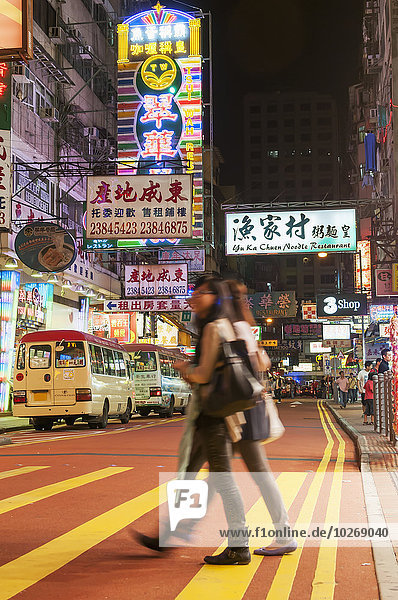 Two girls crossing the road at nighttime in Kowloon district; Hong Kong  China