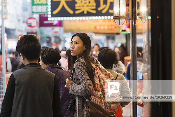 A young woman with backpack among many pedestrians along the busy streets of Kowloon; Hong Kong  China