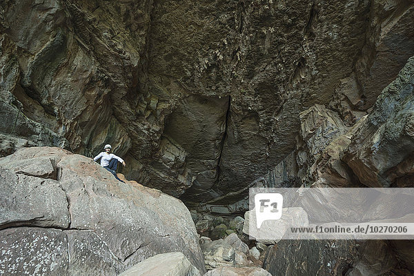 A woman sits at the entrance to a large cave in Toro Toro National Park; Bolivia