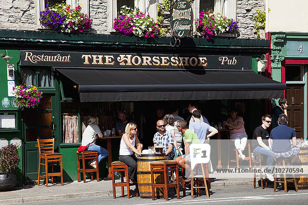 Gäste  die an Fasstischen vor einem Pub sitzen; Kenmare  County Kerry  Irland
