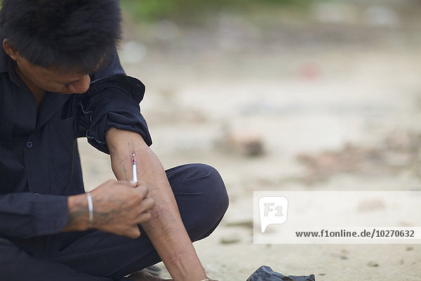 Heroin addict injects; Phnom Penh  Cambodia