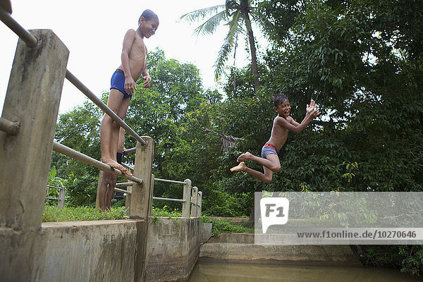 Children jumping into water from a fence; Battambang  Cambodia