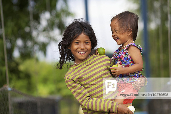 Ein Mädchen hält seine junge Cousine; Battambang  Kambodscha