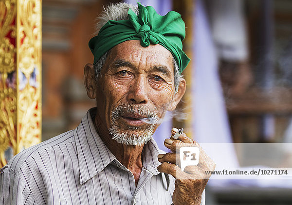Balinese man smoking a cigarette at Tiirta Empul Temple  Tampaksiring  Bali  Indonesia