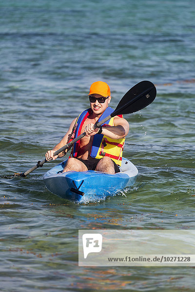 Man in kayak paddling in water; Akumal  Quintana Roo  Mexico
