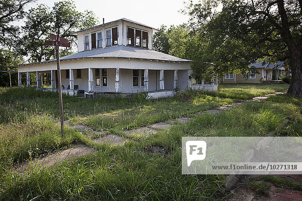 Ein leerstehendes  verlassenes  baufälliges Haus mit zugewachsenem Gras im Hof; Vereinigte Staaten von Amerika